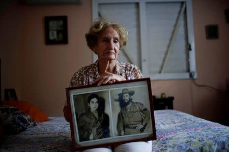 Former rebel Juana Ramirez, 81, poses for a picture holding a photograph of her with her late husband and rebel fighter Luiz Perez, Havana, Cuba, April 4, 2018. REUTERS/Alexandre Meneghini