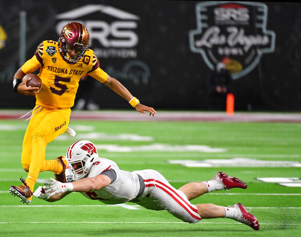 Dec 30, 2021; Paradise, Nevada, USA; Arizona State Sun Devils quarterback Jayden Daniels (5) attempts to evade the tackle of Wisconsin Badgers linebacker Leo Chenal (5) during the 2021 Las Vegas Bowl at Allegiant Stadium. Mandatory Credit: Stephen R. Sylvanie-USA TODAY Sports