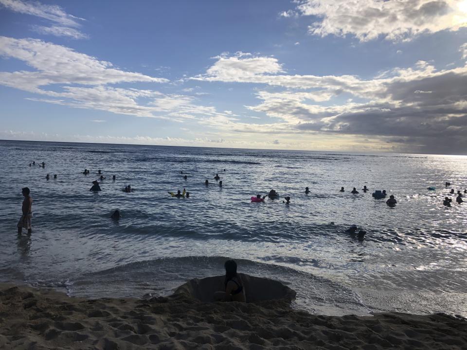 In this photo taken May 13, 2020 in Honolulu, people are in the water at a Waikiki beach. A group of people are helping track down violators of a 14-day quarantine on travelers arriving to Hawaii. (AP Photo/Jennifer Sinco Kelleher)