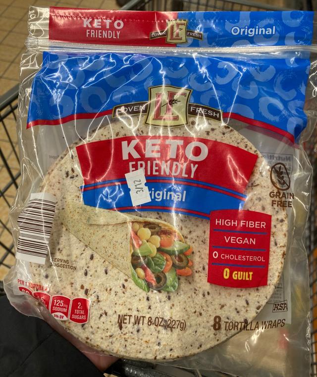hand holding red, blue, and clear package of loven fresh keto wraps at aldi