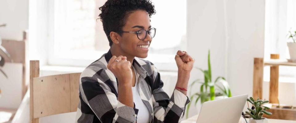 Excited African American woman in glasses read good news online