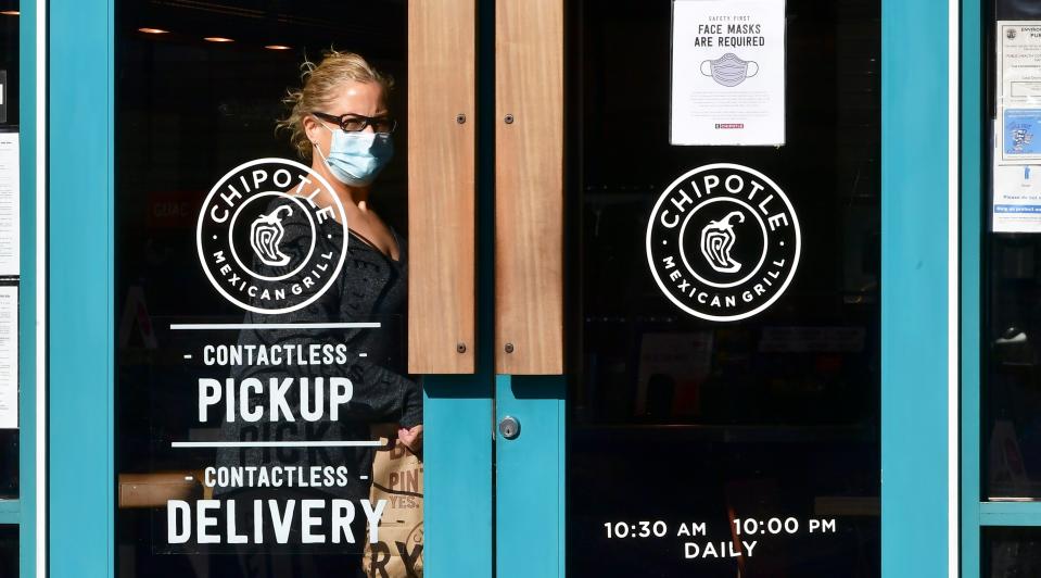 A woman wearing a facemas exits a Chipotle Mexican Grill restaurant with her takeout order on January 14, 2021 in Monterey Park, California. - The national chain restaurant announced its first national hiring event of the year today with a goal of employing 15,000 people for its restaurants across the country. (Photo by Frederic J. BROWN / AFP) (Photo by FREDERIC J. BROWN/AFP via Getty Images)