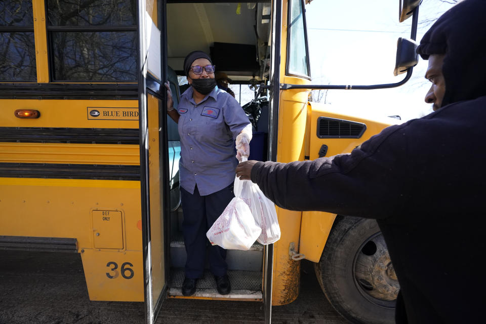 Jefferson County School District Department of Food Services staff member Raquel Mims-Cole, center, hands out several days of bagged lunches to a parent for his children on Wednesday, March 3, 2021 in Fayette, Miss. As one of the nation's most food insecure counties, free breakfast and lunches are provided to students at school and those at home "virtually learning." The meals may be the children's only means of daily sustenance. (AP Photo/Rogelio V. Solis)