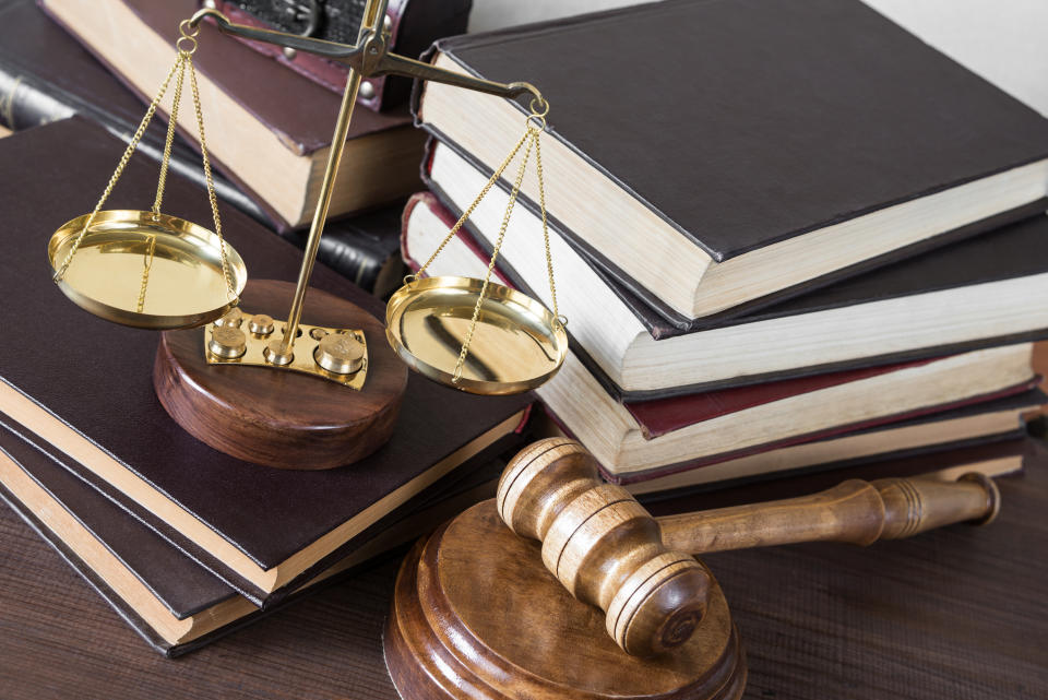 Symbols of law: wood gavel, soundblock, scales and pile of volumetric old books