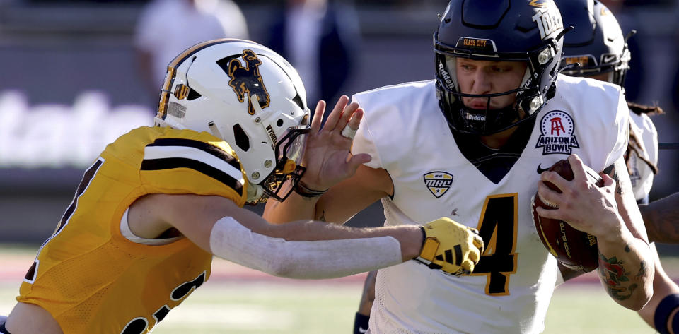 Toledo quarterback Tucker Gleason (4) brushes his way around Wyoming safety Wyett Ekeler (31) on a keeper during the second quarter of the Arizona Bowl NCAA college football game Saturday, Dec. 30, 2023, in Tucson, Ariz. (Kelly Presnell/Arizona Daily Star via AP)