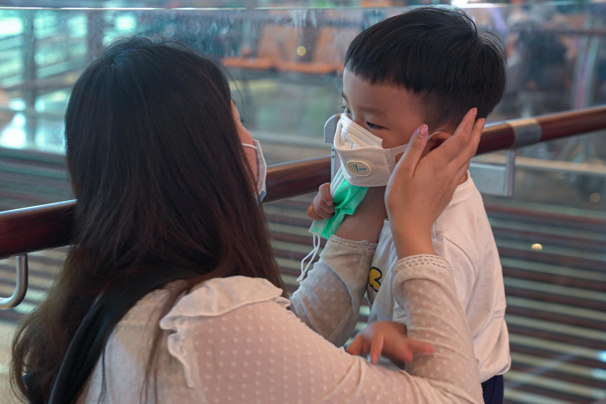 A woman wearing a mask helps her son put on his mask at Changi Airport here on 25 January, 2020. (PHOTO: Getty Images)