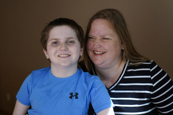 Lisa Manwell poses with her son John Jinks, 12, at their home in Canton, Mich., Wednesday, Sept. 21, 2022. Manwell says her son was improperly removed from his classroom last year because of behaviors that stemmed from his disability. (AP Photo/Paul Sancya)