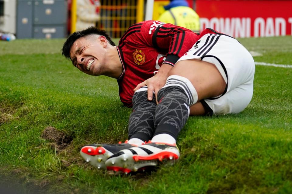 Lisandro Martinez holds his knee in pain after the incident (AP)