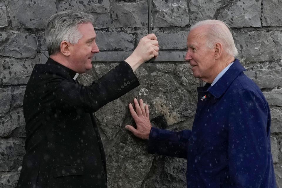 President Joe Biden touches part of the original stonework from the apparition gable at the Knock Shrine as he talks with Father Richard Gibbons, parish priest and rector of Knock Shrine, in Knock, Ireland. Biden visited the shrine on Friday, the last day of his three-day trip to Ireland.