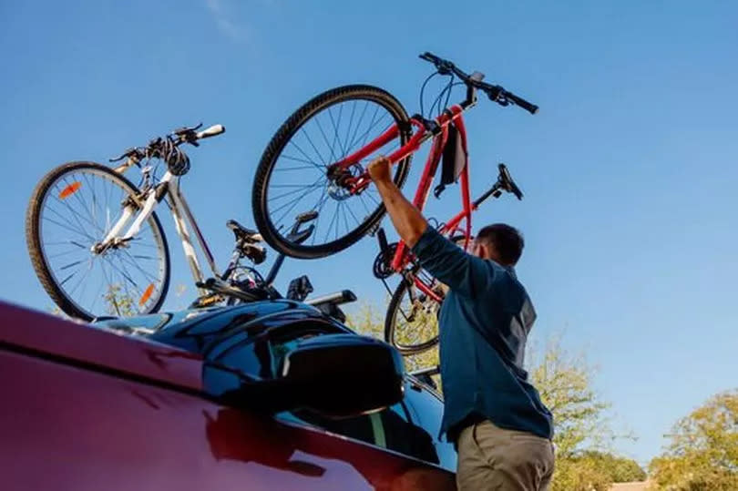 A man putting bikes onto a roof rack