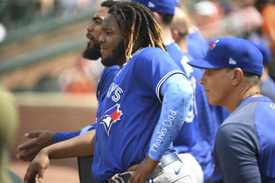 Toronto Blue Jays Vladimir Guerrero Jr. looks on from the dugout while wearing an arm sleeve with the words "Thanks Dad" inscribed on it during a baseball game against the Baltimore Orioles, Sunday, June 20, 2021, in Baltimore. (AP Photo/Terrance Williams)