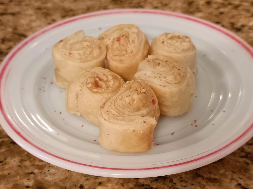 Rolls of puff pastry on a white plate with a red rim