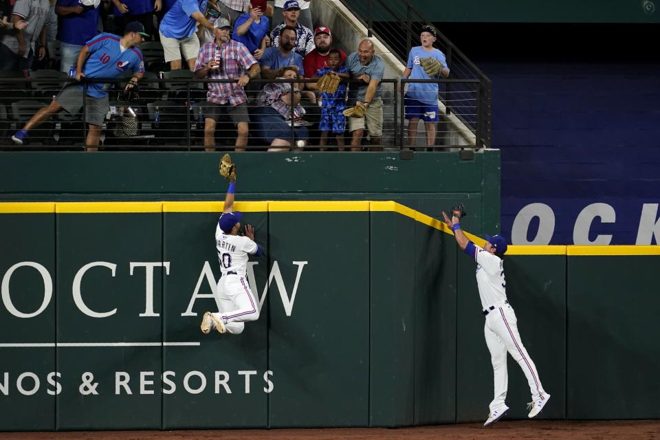 Texas Rangers left fielder Jason Martin (50) and center fielder DJ Peters, right, each make a play for a solo home run hit by Oakland Athletics' Mitch Moreland in the seventh inning of a baseball game in Arlington, Texas, Saturday, Aug. 14, 2021. (AP Photo/Tony Gutierrez)