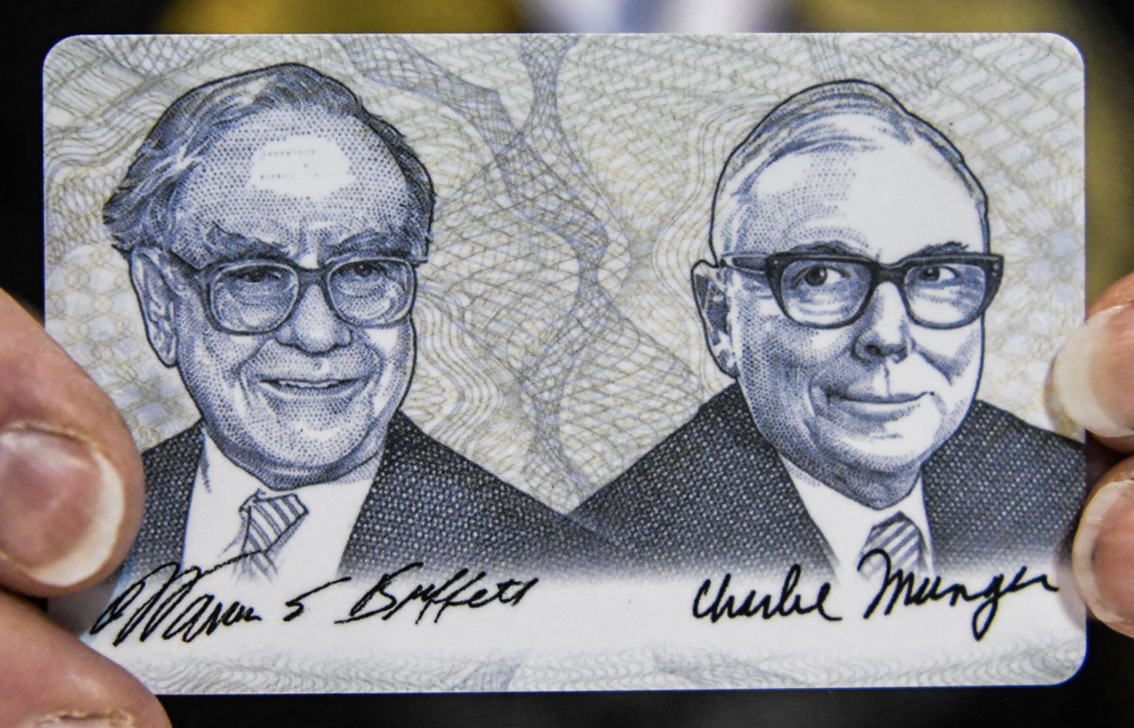 A woman shows a card with photos of Warren Buffett (L) and Charlie Munger (R) during the Shareholder Shopping Day at the Berkshire Hathaway Shareholders Meeting at CHI Health Center in Omaha, Nebraska on April 29, 2022. (Photo by CHANDAN KHANNA / AFP) 