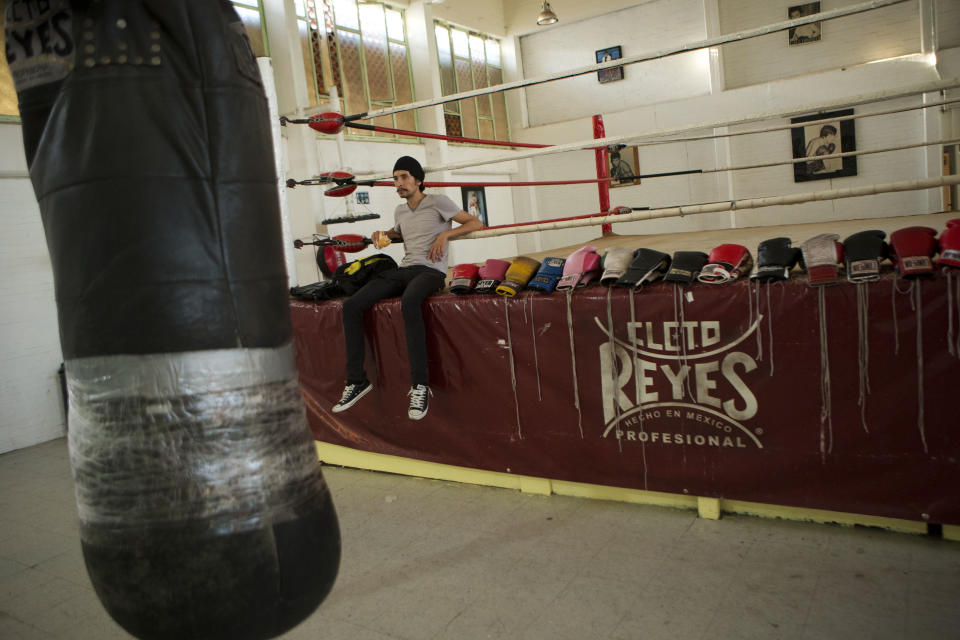 In this April 11, 2014 photo, actor Raul Briones rests in a boxing gym as visitors watch a video on the history and significance of boxing to the Tepito neighborhood of Mexico City. One visitor, Christian Pimentel, who works in marketing and lives in a middle-class neighborhood of the capital, said he had gone shopping in Tepito during the daytime with his family as a kid, but always believed it too dangerous to visit after sundown. "The play helped me see there are good people in Tepito, there are kind people, people struggling to improve their situation." (AP Photo/Rebecca Blackwell)