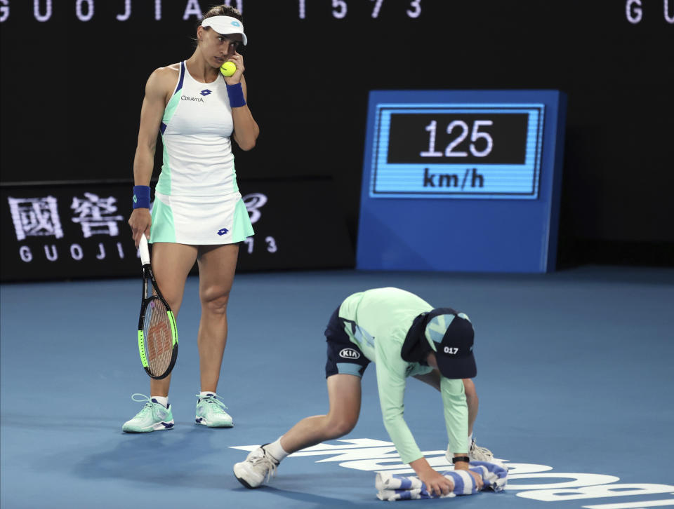 Lesia Tsurenko of Ukraine watches as a ball boy dries the court during her first round singles match against Australia's Ashleigh Barty at the Australian Open tennis championship in Melbourne, Australia, Monday, Jan. 20, 2020. (AP Photo/Lee Jin-man)