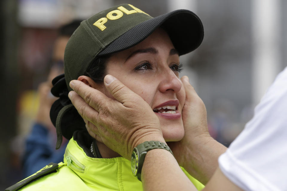 A man attending a march to repudiate violence embraces the face of a crying police officer providing routine security for the march in Bogota, Colombia, Sunday, Jan. 20, 2019. A car bombing at a Bogota police academy that authorities have attributed to rebels of the National Liberation Army killed 21 people and left dozens more wounded on Jan. 17. (AP Photo/Fernando Vergara)