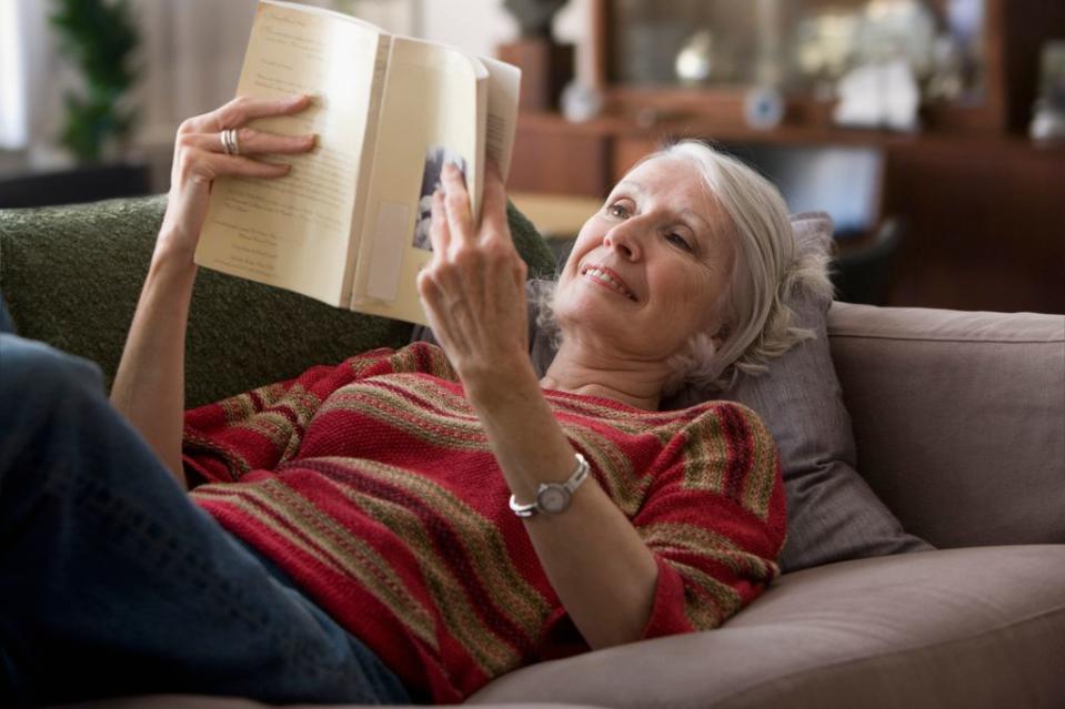 mujer madura relajada leyendo en un sofá