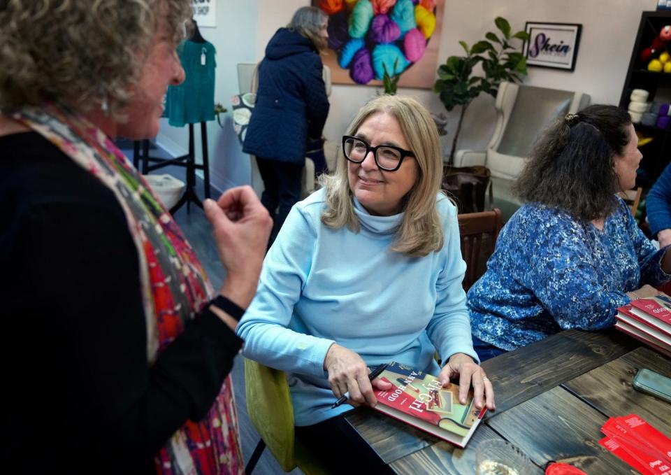 Author Ann Hood, center, signs her new new memoir, "Fly Girl," for Elaine Land at a book event at Skein Yarn Shop in East Greenwich.