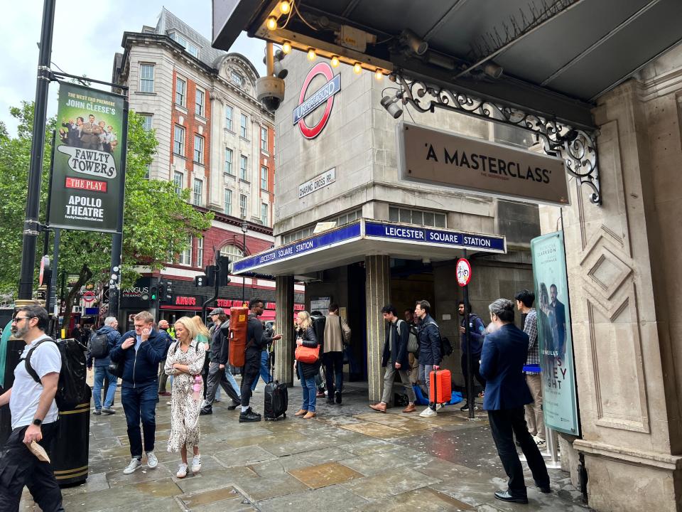 A crowd of people walking past Leicester Square Underground Station in London