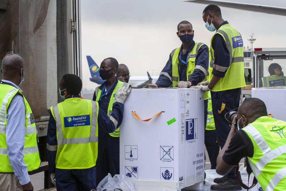 FILE - In this March 3, 2021, file photo, AstraZeneca COVID-19 vaccines are received by airport workers at the airport in Kigali, Rwanda. The COVAX global initiative is providing vaccines to poorer countries lacking the clout to negotiate for them on their own, but on March 25, COVAX announced a major setback in its vaccine rollout because a surge in infections in India had caused the Serum Institute of India to cater to domestic demand, resulting in a delay in global shipments of up to 90 million doses. (AP Photo/Muhizi Olivier, File)