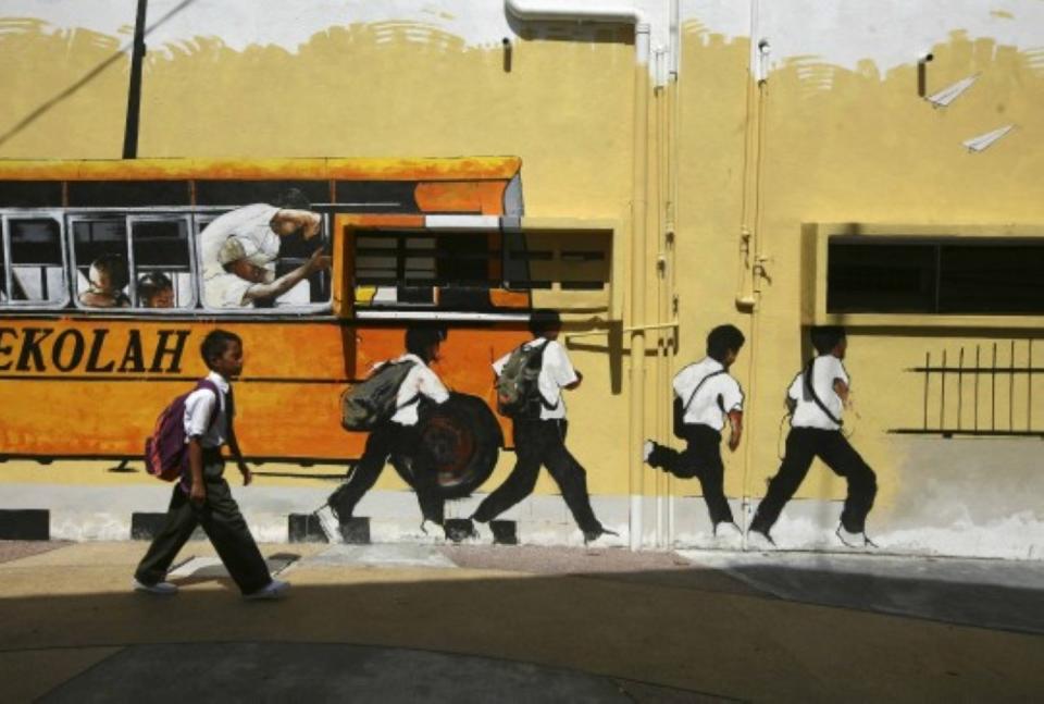 A school boy walks past a street mural depicting a school bus and students in Shah Alam, January 2, 2014. — Reuters pic