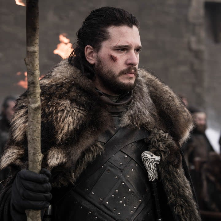 Kit Harington stands with a big stick