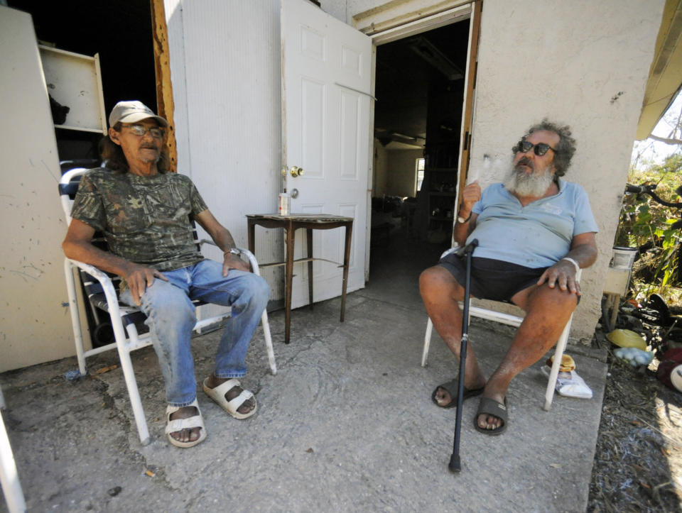 Charlie Lavelle, left, and Michael Money talk outside a hurricane-damaged dormitory at Bread of Life Mission Inc., in Punta Gorda, Fla., on Saturday, Oct. 8, 2022. A few miles meant the difference between life and death when Hurricane Ian struck, and contrasting scenes of recovery and destruction show how a disaster can mean different things to different people. (AP Photo/Jay Reeves)