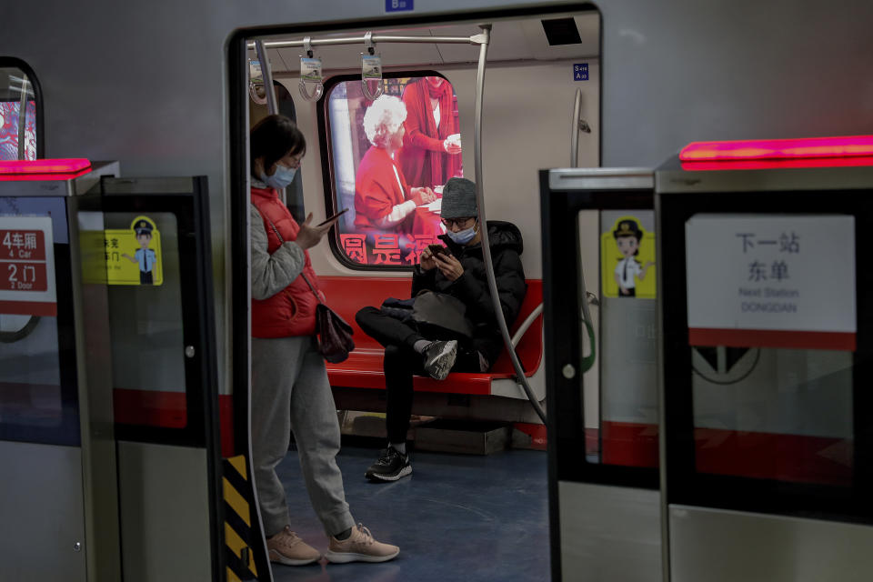 Commuters wearing face masks to help curb the spread of the coronavirus browse their smartphones inside a subway train in Beijing Wednesday, Feb. 10, 2021. China's internet watchdog is cracking down further on online speech, issuing a new requirement that bloggers and influencers have a license before they can publish on certain topics. The rule from the Cyberspace Administration of China that goes into effect later this month is shrinking an already highly limited space for discourse amid heavy censorship of sensitive topics and any perceived criticism of the ruling Communist Party. (AP Photo/Andy Wong)