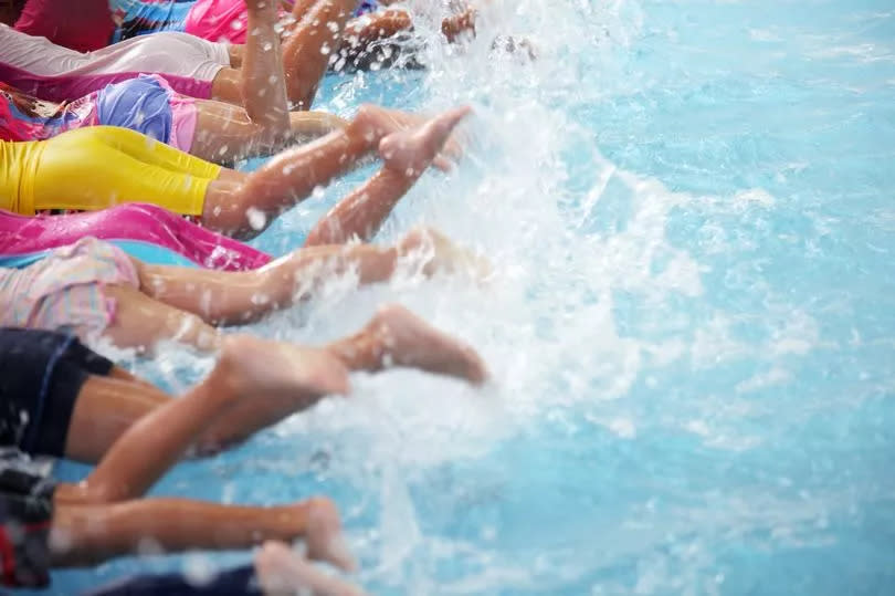 A picture of children's' feet kicking in a swimming pool