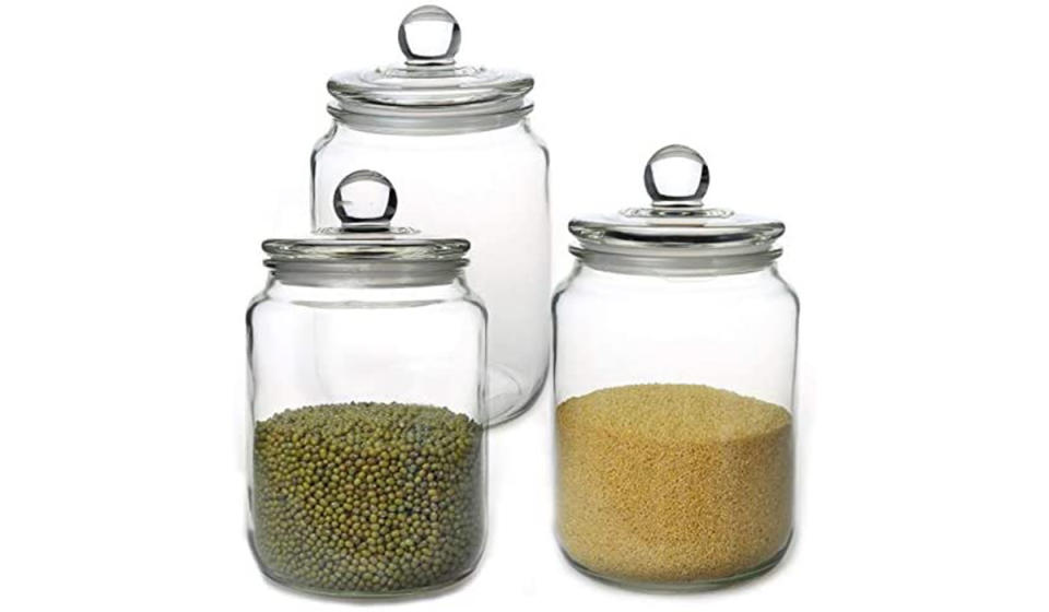 Trio of clear jars with pantry items decanted within and accompanying lids