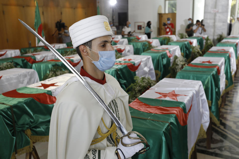 A soldier guards the remains of 24 Algerians at the Moufdi-Zakaria culture palace in Algiers, Friday, July, 3, 2020. After decades in a French museum, the skulls of 24 Algerians decapitated for resisting French colonial forces were formally repatriated to Algeria in an elaborate ceremony led by the teary-eyed Algerian president. The return of the skulls was the result of years of efforts by Algerian historians, and comes amid a growing global reckoning with the legacy of colonialism. (AP Photo/Toufik Doudou)