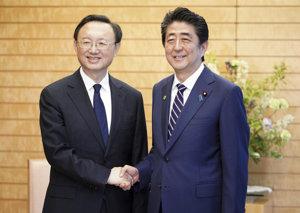 Chinese State Councilor Yang Jiechi, left, and Japanese Prime Minister Shinzo Abe, right, shake hands at Abe's official residence in Tokyo Friday, May 17, 2019. (AP Photo/Eugene Hoshiko, Pool)