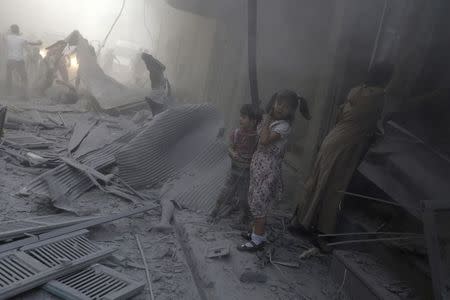 Children react beside a dead body under rubble at a site hit by what activists said were two airstrikes by forces loyal to Syria's President Bashar al-Assad in Douma in eastern al-Ghouta, near Damascus August 3, 2014. REUTERS/Bassam Khabieh