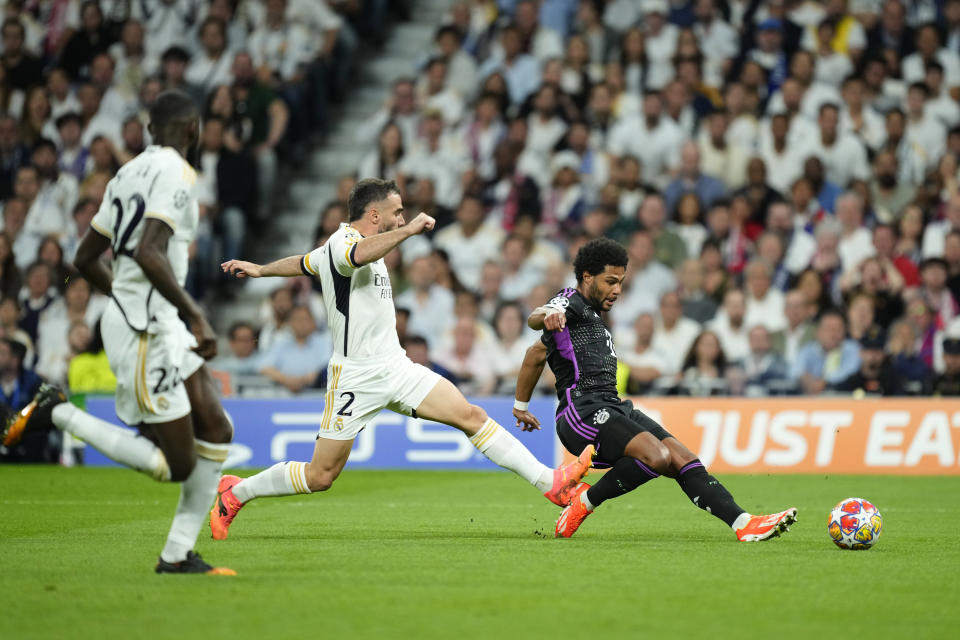 Bayern's Serge Gnabry, right, challenges for the ball with Real Madrid's Dani Carvajal, centre, during the Champions League semifinal second leg soccer match between Real Madrid and Bayern Munich at the Santiago Bernabeu stadium in Madrid, Spain, Wednesday, May 8, 2024. (AP Photo/Jose Breton)