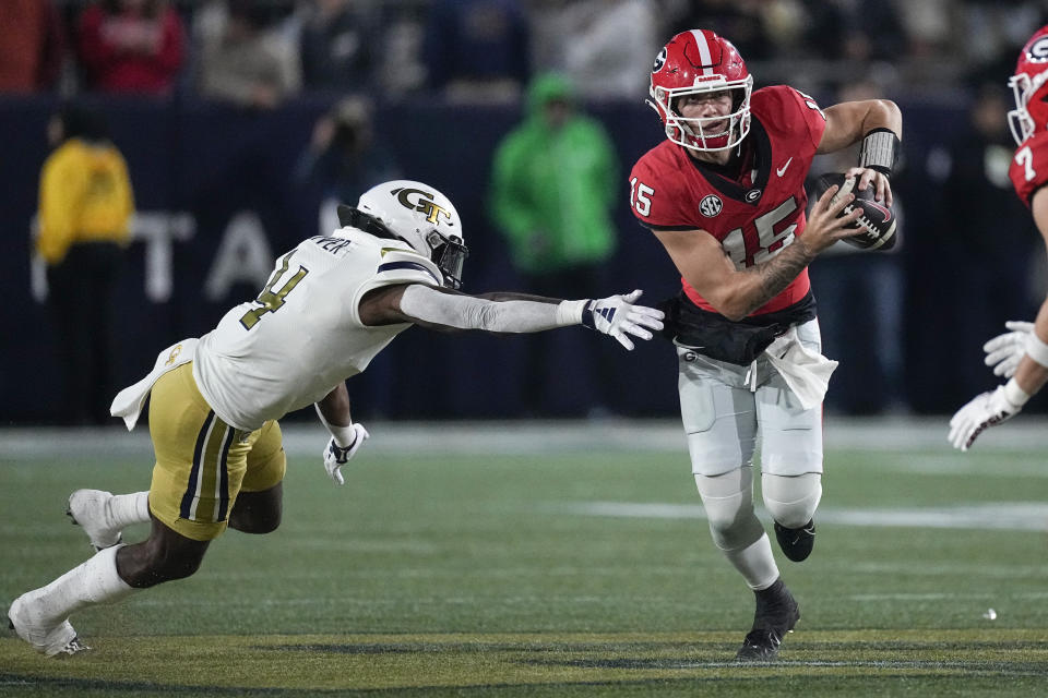 Georgia quarterback Carson Beck (15) tries to escape from Georgia Tech linebacker Braelen Oliver (4) during the second half of an NCAA college football game, Saturday, Nov. 25, 2023, in Atlanta. (AP Photo/John Bazemore)