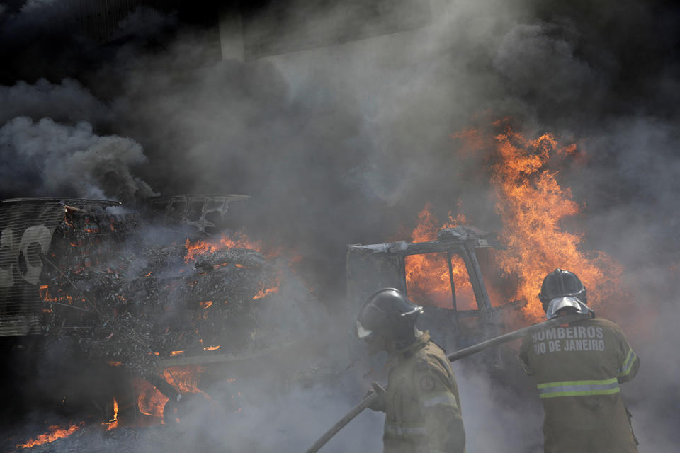 Firefighters try to extinguish a fire during violent clashes in Rio de Janeiro