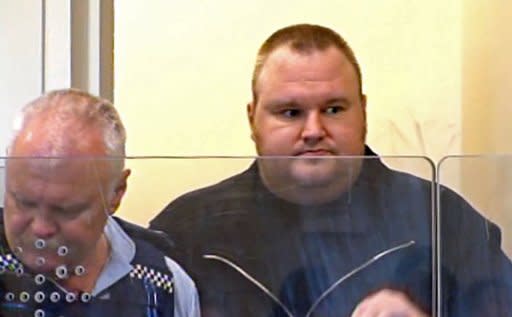 A TV grab showing Internet guru and founder of Megaupload.com, Kim Schmitz, also known as "Kim Dotcom" (right), escorted by a policeman as he appears in an Auckland district court in New Zealand on Friday. New Zealand police seized a treasure trove of luxury goods from Dotcom on Friday as he and three other suspected Internet pirates wanted in the United States appeared in court