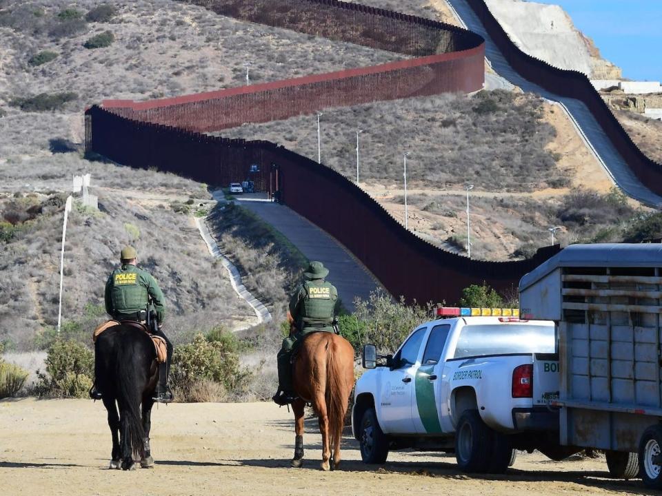 US Border Patrol agents on horses near fence