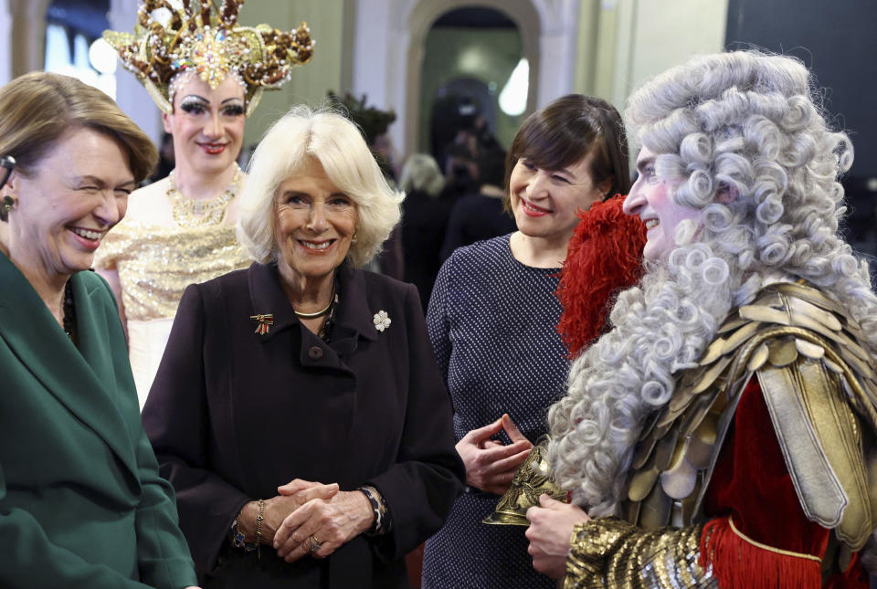 Camilla, Queen Consort the wife of Britain's King Charles III and Germany's first lady Elke Buedenbender react as they talk with a Komische Oper Berlin performer, next to Managing Director Susanne Moser, during a tour of the opera house in Berlin, Germany, March 30, 2023. (Christian Mang/Pool Photo via AP)