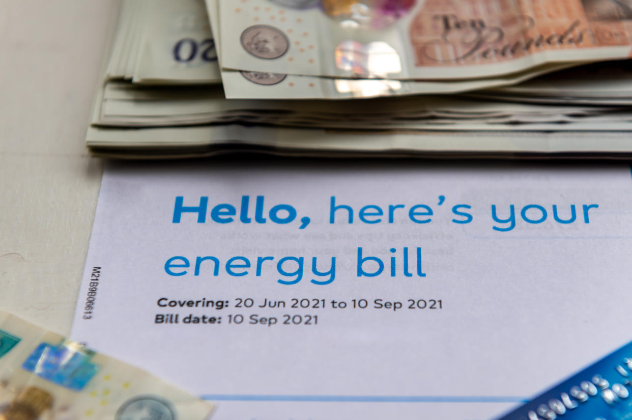 Close up of a energy bill with a pile of bank notes and a payment card. Rising energy cost concept.