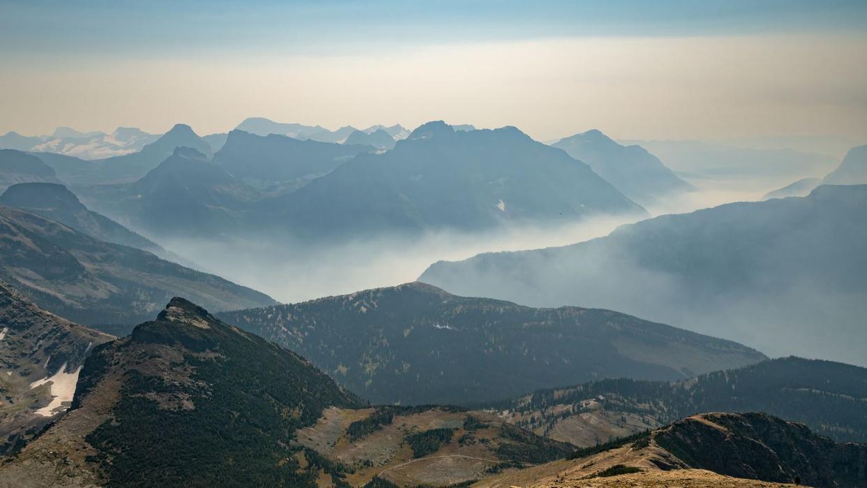 wildfire smoke fills up valley in vast mountains of glacier national park, montana, usa on a hot dry day of summer climate change impact global warming