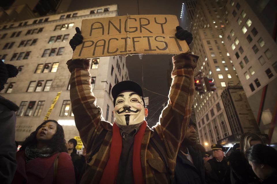 A demonstrator wearing a Guy Fawkes mask walks up 6th Ave as he protests against the police in the Manhattan borough of New York December 23, 2014. Mayor Bill de Blasio's attempts to soothe a city dismayed by the slaying of two officers were further rebuffed on Tuesday as protesters defied his call to suspend what have become regular demonstrations over excessive police force. REUTERS/Carlo Allegri (UNITED STATES - Tags: CIVIL UNREST CRIME LAW TPX IMAGES OF THE DAY)