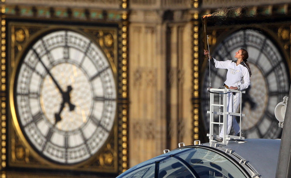 In this photo provided by LOCOG, Amelia Hempleman-Adams poses with the Olympic Flame on top of a London Eye pod on the Torch Relay leg through London. Opening Ceremonies for the 2012 London Olympics will be held Friday July 27. (AP Photo/LOCOG, Lewis Whyld)