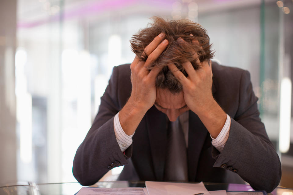 A worker hangs their head during a stressful moment in the office