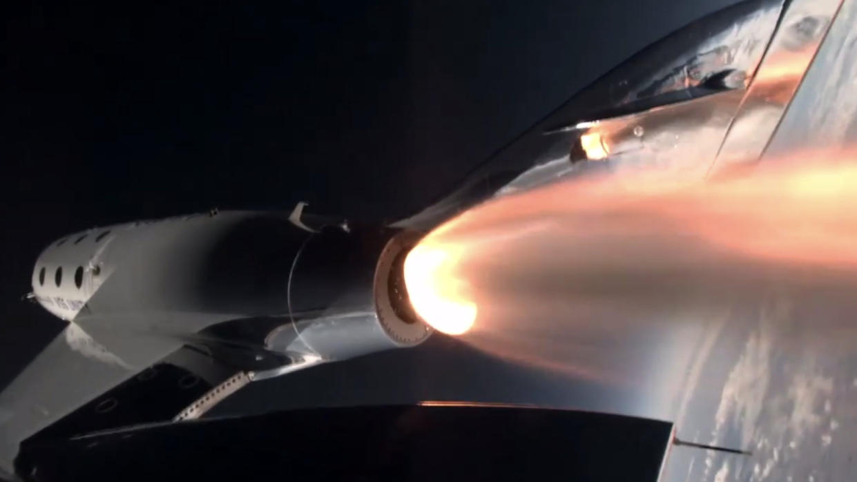  A space plane lights its rocket motor in space, with the curve of earth in the background. 