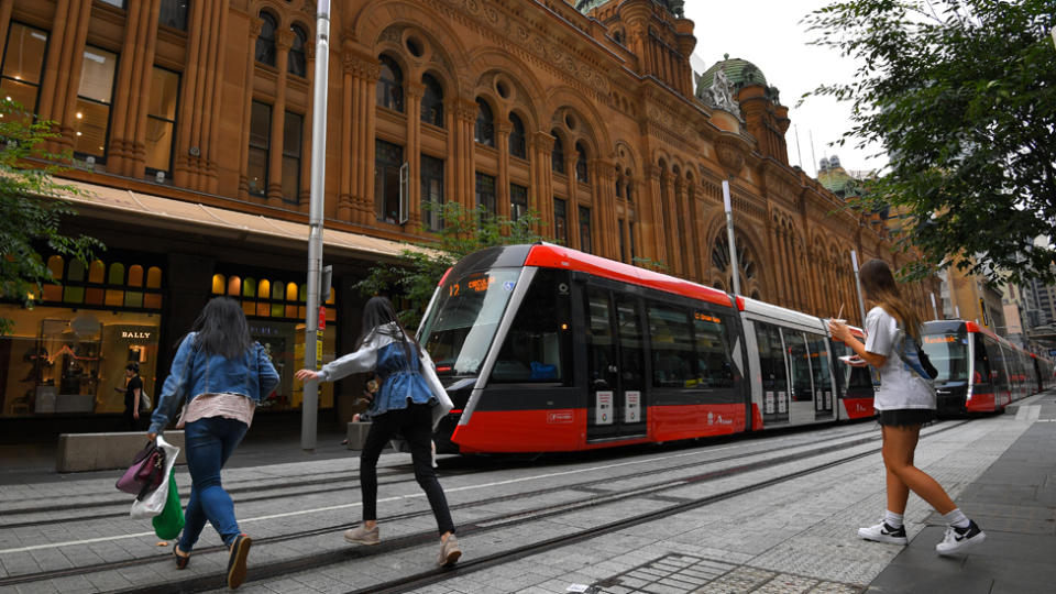 Pedestrians cross tram tracks in Sydney. An illegal crossing now attracts a fine of $76.