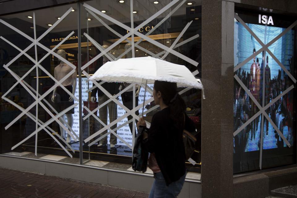 A woman walks past the windows of a boutique store that have been taped-up in preparation for Typhoon Usagi at Tsim Sha Tsui shopping district in Hong Kong