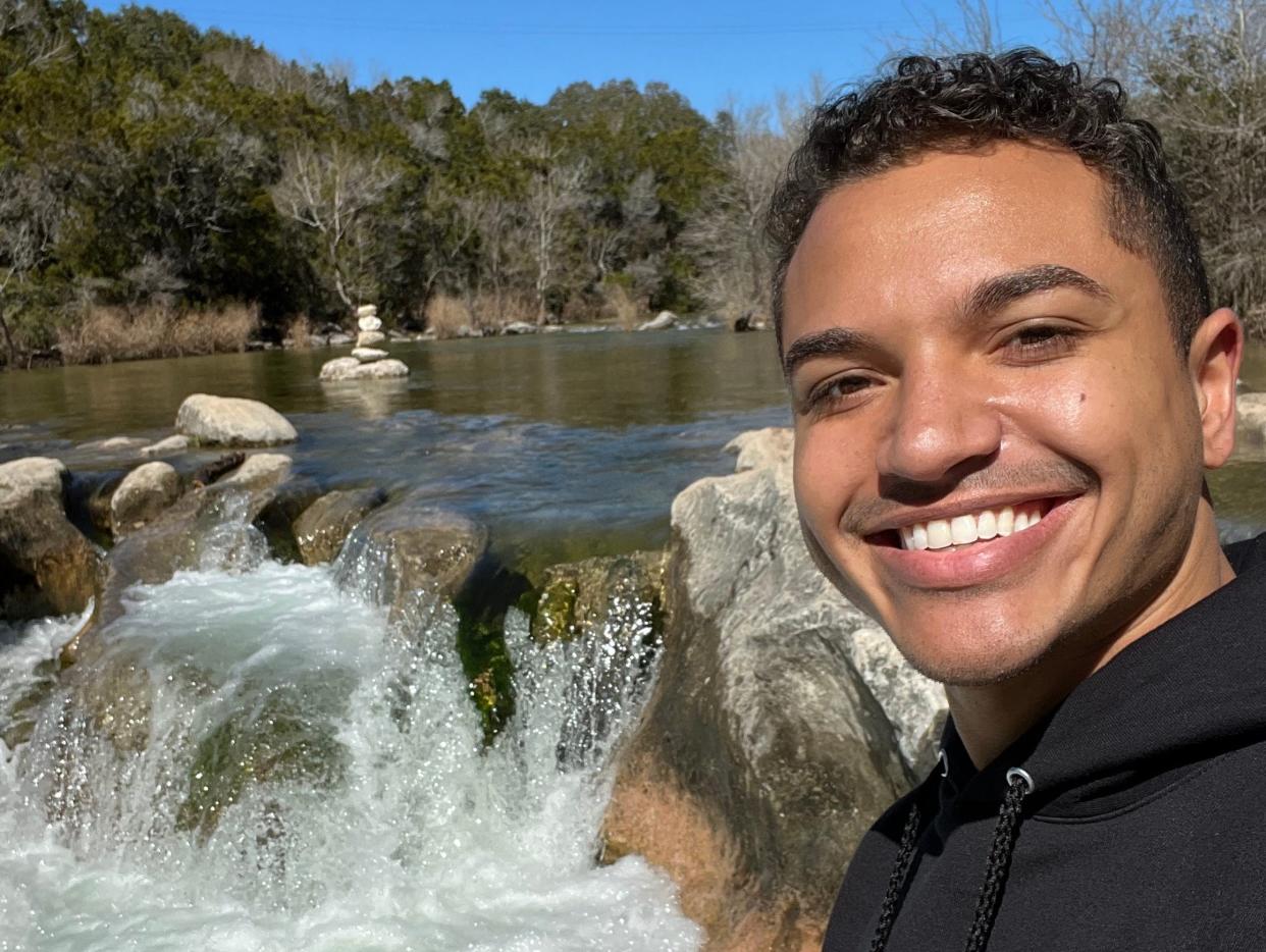 Quishon Walker in a black hoodie in front of a small waterfall.