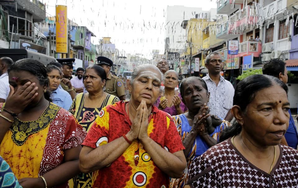 Sri Lankan Catholics pray standing on a road during a brief holly mass held outside the exploded St. Anthony's Church marking the seventh day of the Easter Sunday attacks in Colombo, Sri Lanka, Sunday, April 28, 2019. Sri Lanka's Catholics on Sunday awoke preparing to celebrate Mass in their homes by a televised broadcast as churches across the island shut over fears of militant attacks, a week after the Islamic State-claimed Easter suicide bombings. (AP Photo/Eranga Jayawardena)